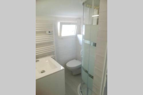 une salle de bain blanche avec des toilettes et un lavabo dans l'établissement T2 à Menton Vue mer proche Plage, à Menton