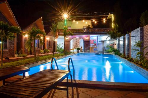 una piscina por la noche con un banco en Phong Nha Hillside View Bungalow, en Phong Nha