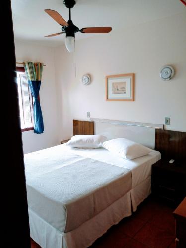 a bedroom with a white bed with a ceiling fan at Pousada Japeju in Capão da Canoa