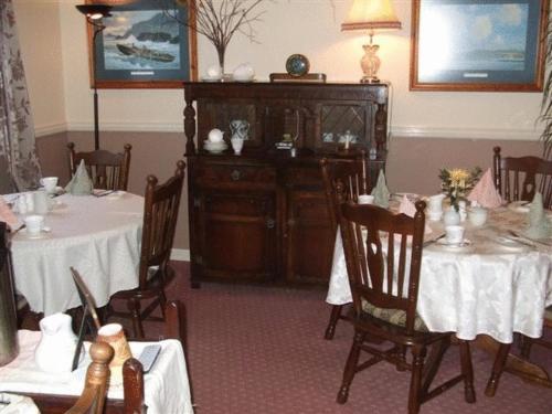 Windway House في كيلارني: غرفة طعام مع طاولتين وخزانة