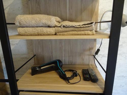 a hair dryer on a shelf next to a remote control at La Lauriére in Treize-Vents