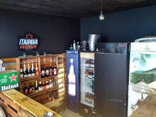 a bar with a refrigerator and a bottle of beer at Jeremias Hostel Bar in Vila Velha