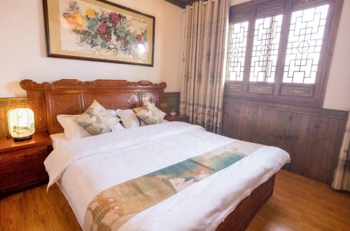 1 dormitorio con 1 cama grande y cabecero de madera en 杏竹斋客栈, en Yi
