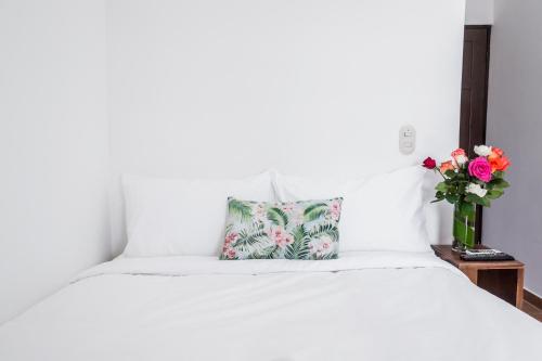 a white bed with a pillow and a vase of flowers at The Palms At Coco Beach in Coco