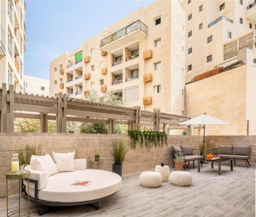 een patio met een witte bank en tafels en een gebouw bij Mr. Agrippa - By TLV2GO in Jeruzalem