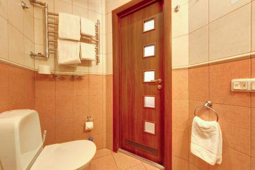 baño con aseo y puerta con toallas en Atria Guest House, en San Petersburgo