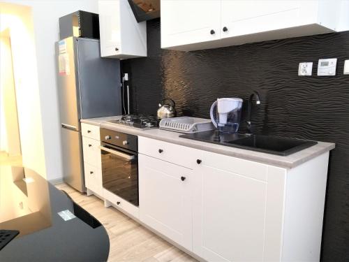 a white kitchen with a sink and a refrigerator at Apartament Sikorki in Nowy Sącz