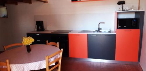 a kitchen with a table and a sink and a kitchen with red cabinets at gite 2 ou 3 personnes - campagne in Bourbriac