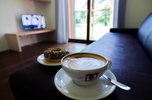 a cup of coffee and a donut on a table at Komodo short stay apartments in Trento