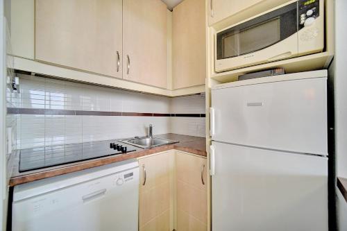 La cuisine est équipée d'un réfrigérateur blanc et d'un four micro-ondes. dans l'établissement IMMOGROOM - sea view - Pool - Terrace - Parking - Air conditioning, à Cannes