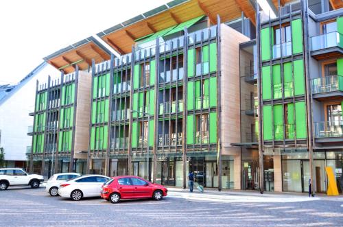 a large building with cars parked in a parking lot at Komodo short stay apartments in Trento