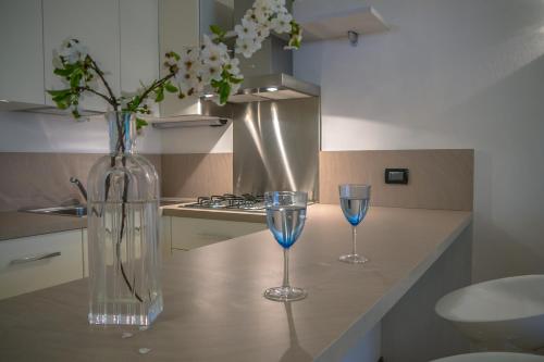 due bicchieri da vino e un vaso con fiori sul bancone della cucina di Residence Oasi a Manerba del Garda