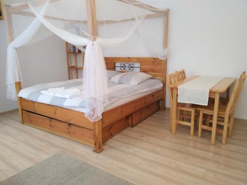 - une chambre avec un lit à baldaquin et une table dans l'établissement Apartament Pijarska, à Nowy Sącz