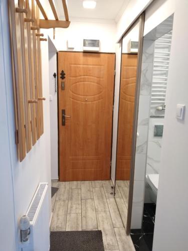 un couloir avec une porte en bois et une salle de bains. dans l'établissement Apartament Pijarska, à Nowy Sącz