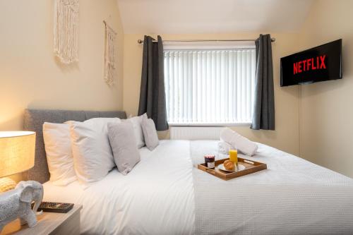 a bedroom with a bed with a tray of food on it at Summerfield House - Elegant house with garden near NEC, JLR, Solihull in Solihull