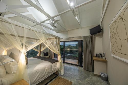 a bedroom with a canopy bed and a large window at Little Kubu Lodge in Hoedspruit