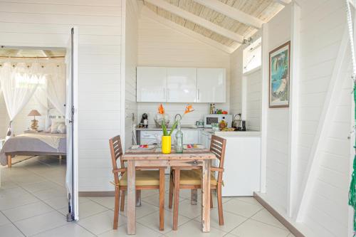 a kitchen and dining room with a table and chairs at Bungalow Vanille Pacane - Vue Mer avec Spa Privé in Les Trois-Îlets