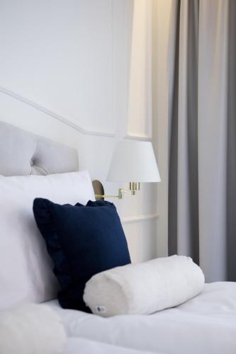a white bed with a blue pillow and a lamp at Mały Sopot Boutique in Iława