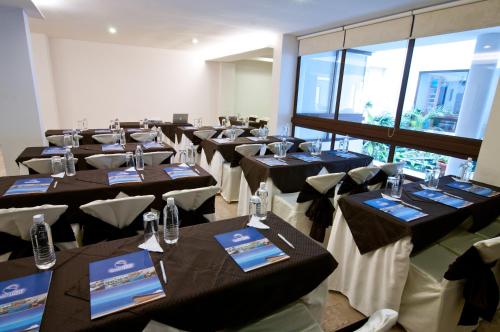 a row of tables in a room with black tables and chairs at Hotel Isla Sol by Solymar in Puerto Ayora