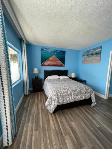 a bedroom with a bed with blue walls and a wooden floor at LA Adventurer Hotel in Inglewood