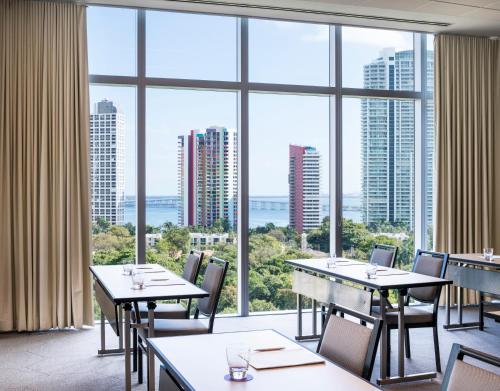 a restaurant with tables and chairs and large windows at Novotel Miami Brickell in Miami