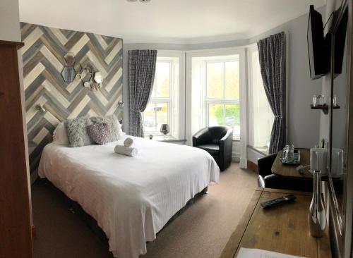 a bedroom with a large white bed and a chair at Alpine Lodge Guest House in Llanberis