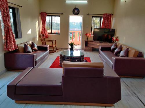 a living room with couches and a flat screen tv at Quinte Hills Residency in Panchgani
