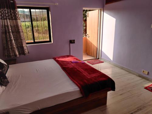 a bedroom with a bed with a red blanket on it at Quinte Hills Residency in Panchgani
