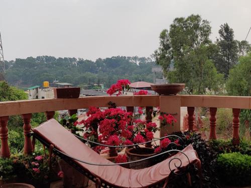 a bunch of flowers on a balcony with a bench at Quinte Hills Residency in Panchgani