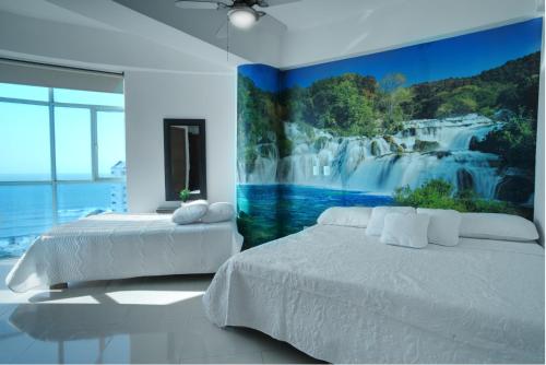 1 dormitorio con 2 camas y una pintura de una cascada en Poseidon Lake Apartments, en Cartagena de Indias