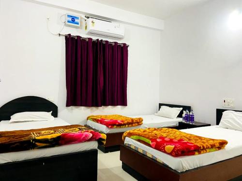 Habitación con 3 camas y cortina roja. en Gaurav guest house en Bodh Gaya