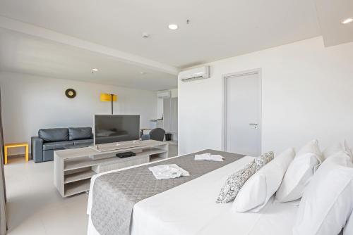 a white bedroom with a bed and a television at Guarujá Vivah in Guarujá