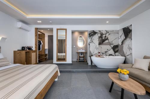 a bedroom with a bed and a tub and a couch at NISSEA Boutique Hotel in Kardamaina
