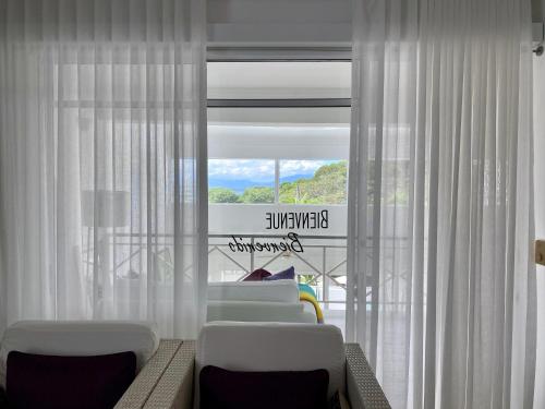 a living room with white chairs and a window at Casa Veintiuno in Sosúa