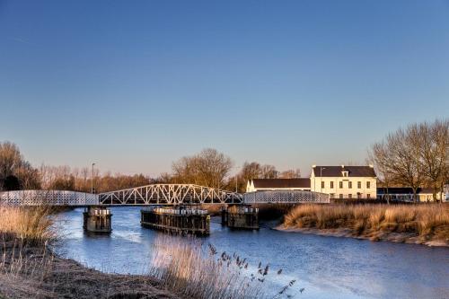 a bridge over a river with houses and buildings at De Koolputten in Waasmunster