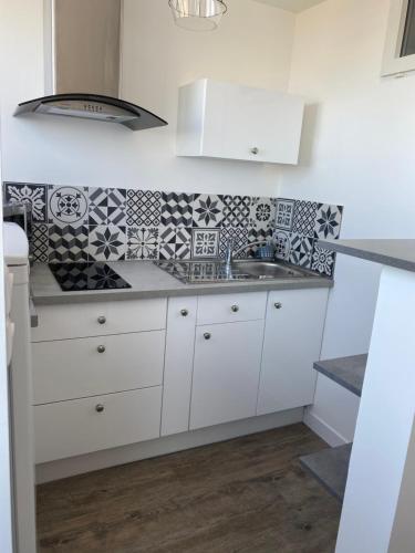 une cuisine avec des armoires blanches et du carrelage noir et blanc dans l'établissement Entre mer et falaises 2, au Tréport