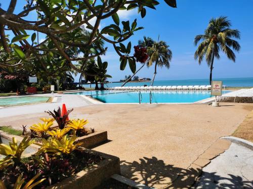 a swimming pool with the ocean in the background at Tanjung Tuan Beach Regency - Hermis Theme in Kampong Baharu