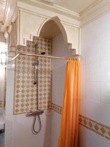 a shower with an orange shower curtain in a bathroom at Casa Natalia in Mecina Fondales