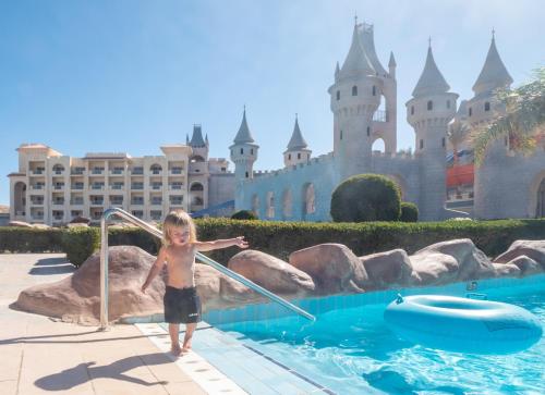 a young boy standing in a pool in front of a castle at Serenity Alma Heights - Ex Serenity Fun City in Hurghada