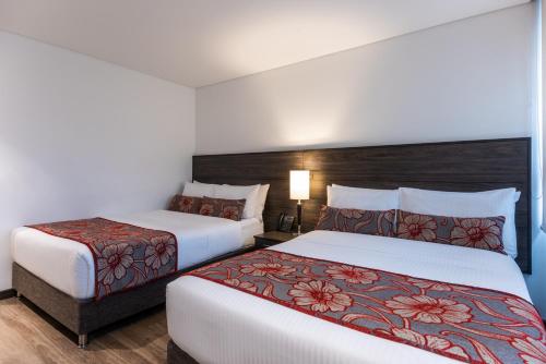 two beds in a hotel room with white walls at AZ Hotel in Bogotá