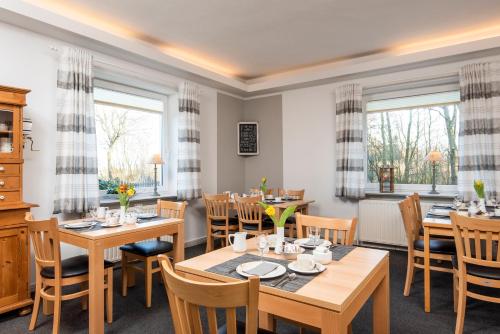 ein Esszimmer mit Tischen, Stühlen und Fenstern in der Unterkunft Hotel-Klanxbüller-Stuben in Neukirchen