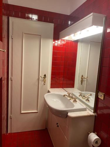 y baño con lavabo, espejo y azulejos rojos. en Villa Del Rosensuite, en Pinzolo