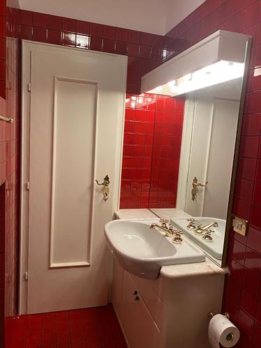 a bathroom with a sink and a mirror and red tiles at Villa Del Rosensuite in Pinzolo