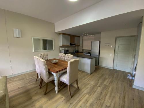 a kitchen and dining room with a wooden table and chairs at 504 The HeroldsBay in Herolds Bay