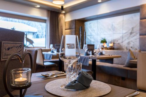 a table with a wine glass on a table in a restaurant at GenussHotel Sonnblick in Sankt Leonhard im Pitztal