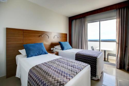 a hotel room with two beds and a window at Advanced Hotel & Flats Cuiabá in Cuiabá