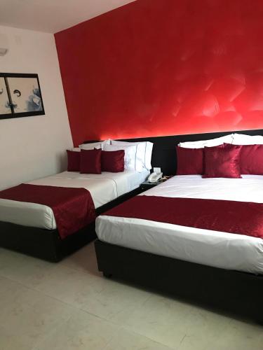 two beds in a hotel room with red walls at Quinta Santa Anita in Playa del Carmen