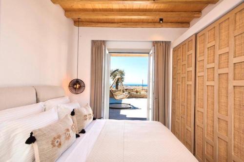 Blue Orchid Villa Mykonos في كالافاتيس: غرفة نوم مع سرير وإطلالة على المحيط