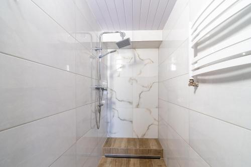 a shower in a bathroom with white tiles at Strumyk in Lubawka