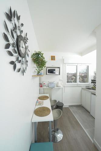 une cuisine avec une table et une horloge au mur dans l'établissement Appartement - Cosy T1 bis, proche de Paris, à Villeneuve-la-Garenne